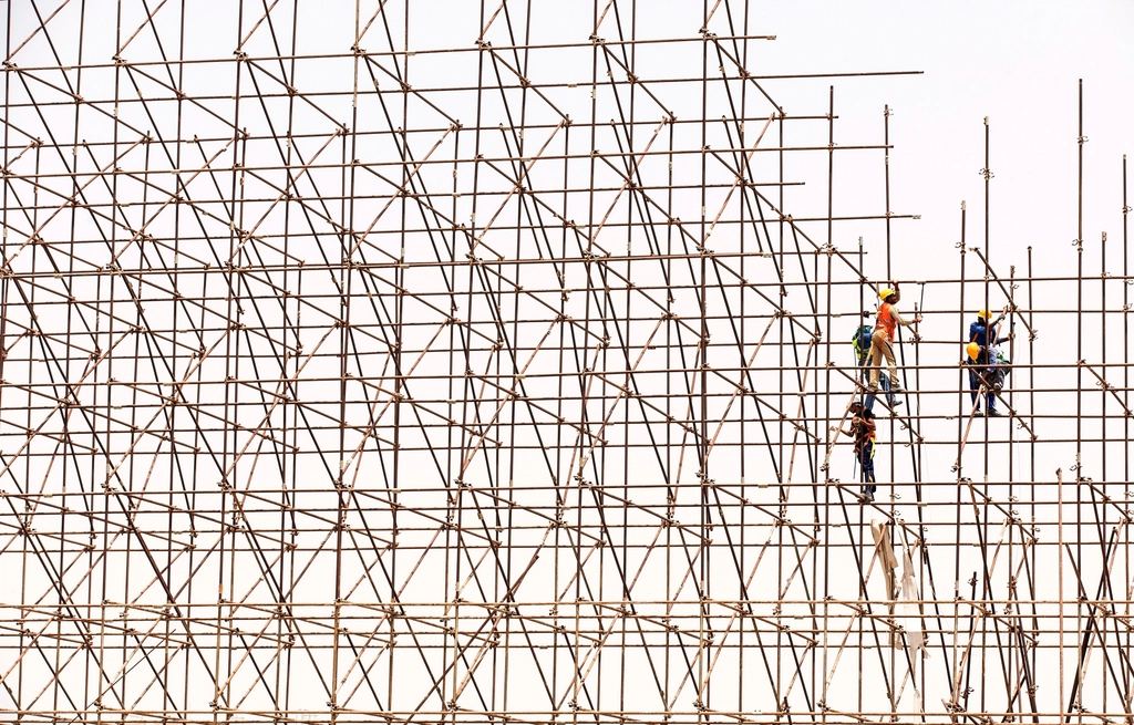 足場の上で作業する職人たち（参考写真）